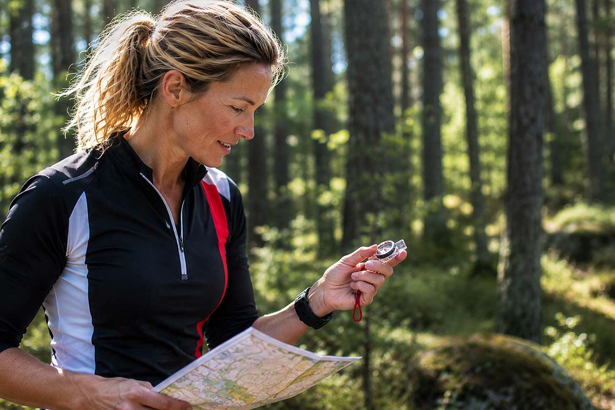 Helena utför orientering i skogen kollar på kompas